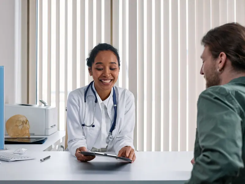 A smiling doctor talking with a patient across a desk